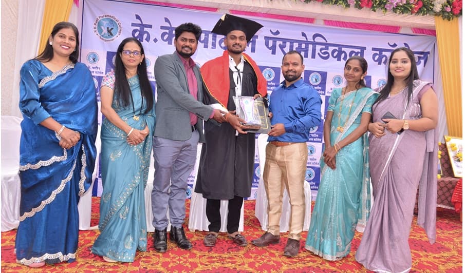 Male graduate candidate receiving convocation plaque on stage