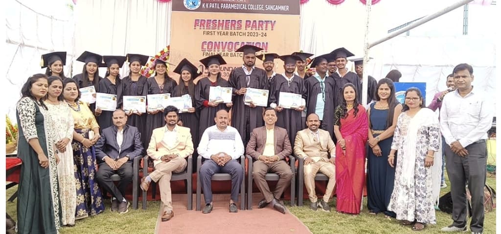 Full stage group photo of graduates in gowns and seated faculty
