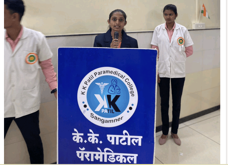 Female faculty anchor holding microphone at KK Patil Paramedical podium